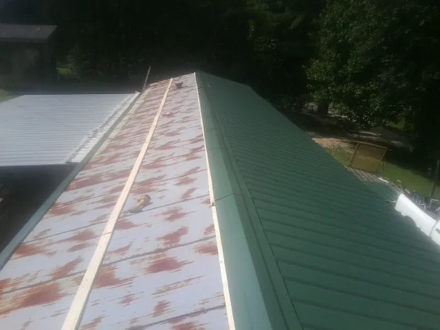 Old rusted panels beside newly installed green metal roofing — Wind Damage Roof Repair by Roofing Brothers in Purcellville