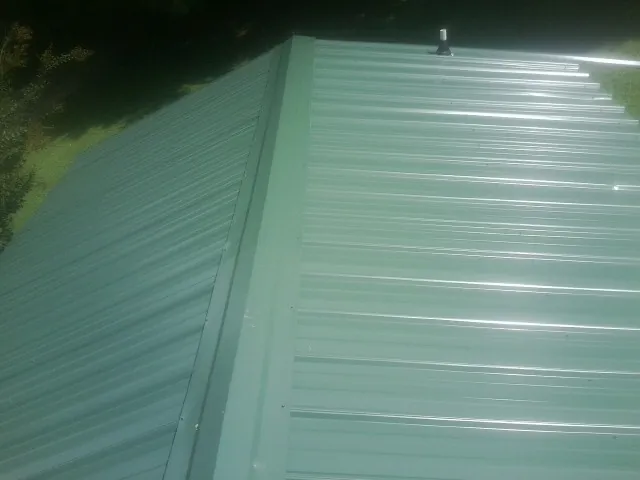 New green metal panels meeting at the ridge of a roof — Flat Roof Repair work by our crew in Purcellville