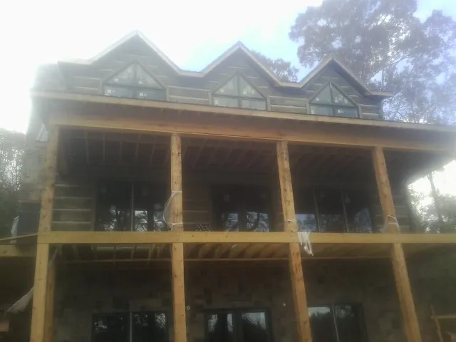 Dormers and porch framing on a large log home under construction — Roof Coating work by our crew in Purcellville