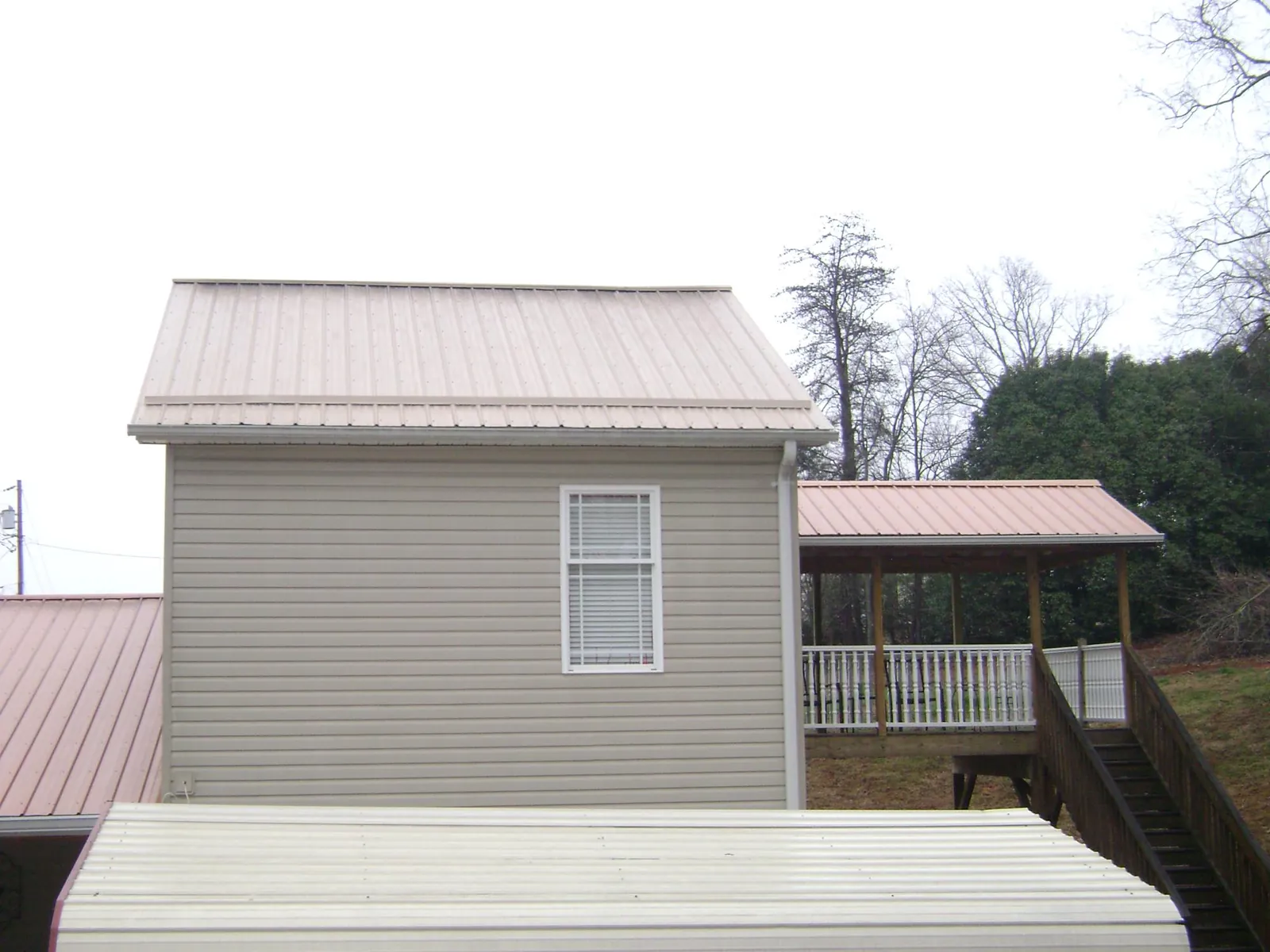Tan metal roofs on a two story addition and attached porch, from a Roof Replacement job in Purcellville