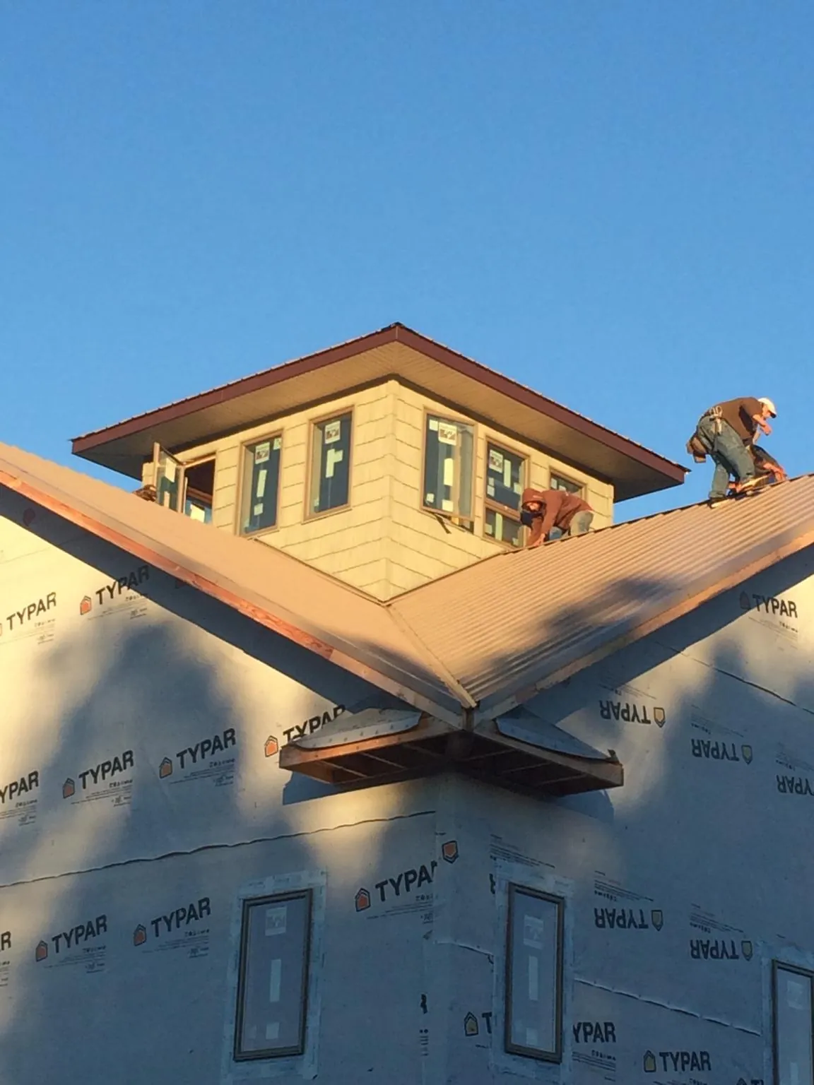 Roofers working around a rooftop cupola on a new metal roof at sunset — Roof Waterproofing in Purcellville by Roofing Brothers